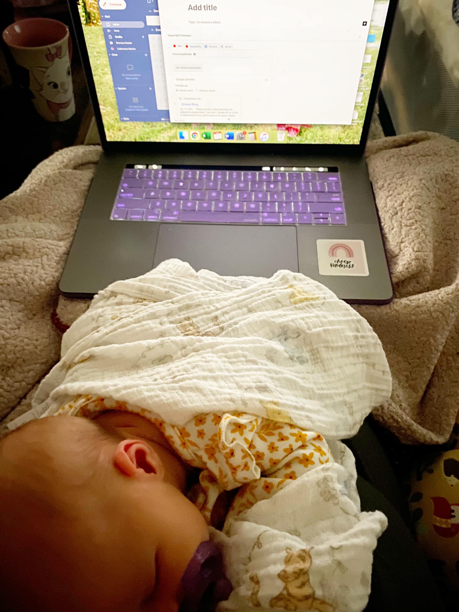 a small business owner who is a mom with her baby on her chest answering emails on her computer